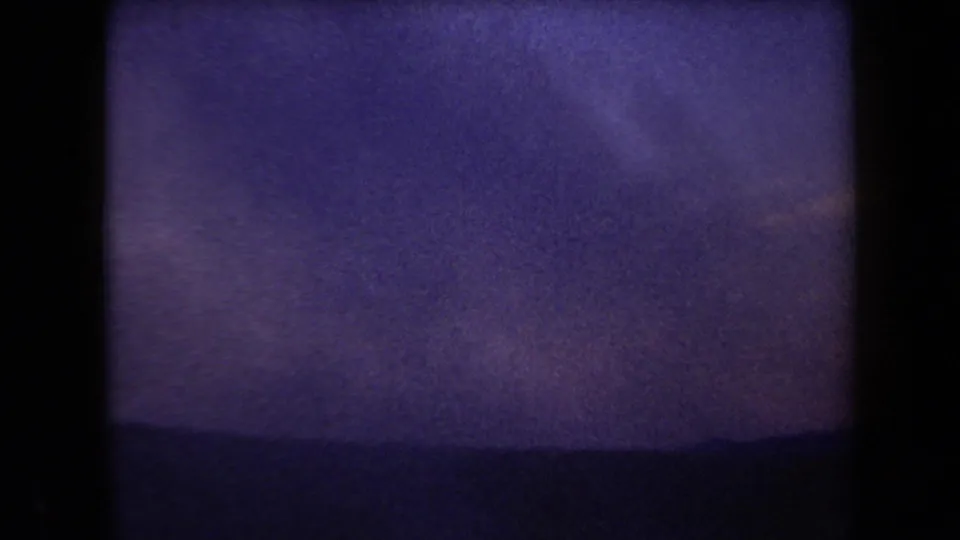 1958 Arizona 8mm frame of a low desert mountain horizon under a pale, purple-shifted sky.