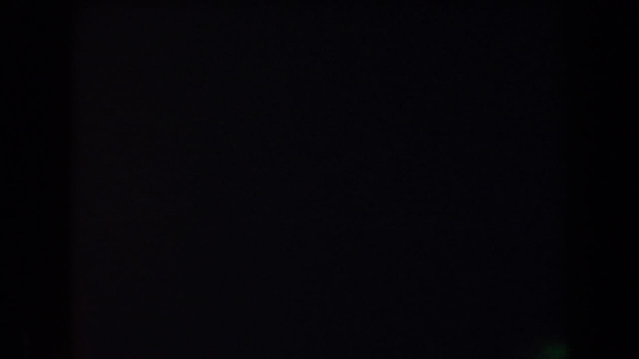 Underexposed 8mm frame from the nighttime Arizona camping clip, with the scene almost entirely fading into darkness.