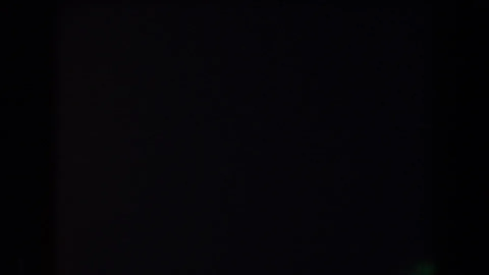Underexposed 8mm frame from the nighttime Arizona camping clip, with the scene almost entirely fading into darkness.