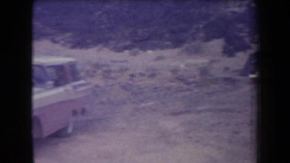 1958 Arizona home-movie frame showing a two-tone vehicle at the edge of a rough, rocky outdoor parking area.