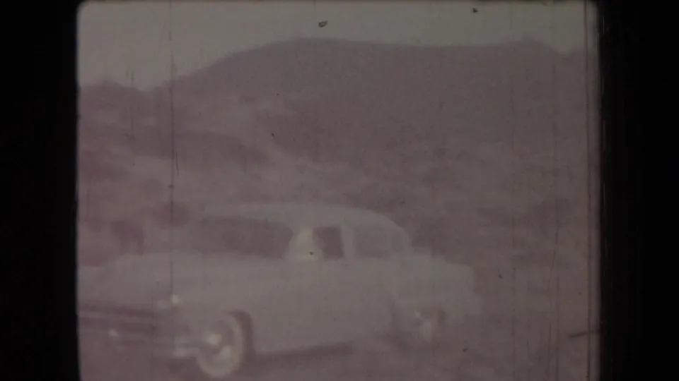 1958 Arizona 8mm frame showing a soft, faded view of a light-colored car against low arid hills.