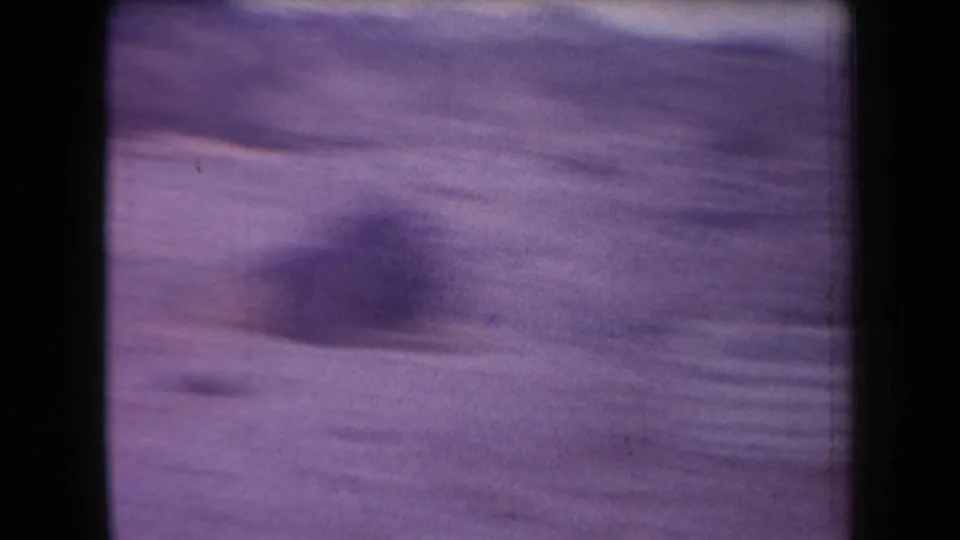 1958 Arizona 8mm frame with a blurred purple desert view and an indistinct figure or shadow in the lower center.