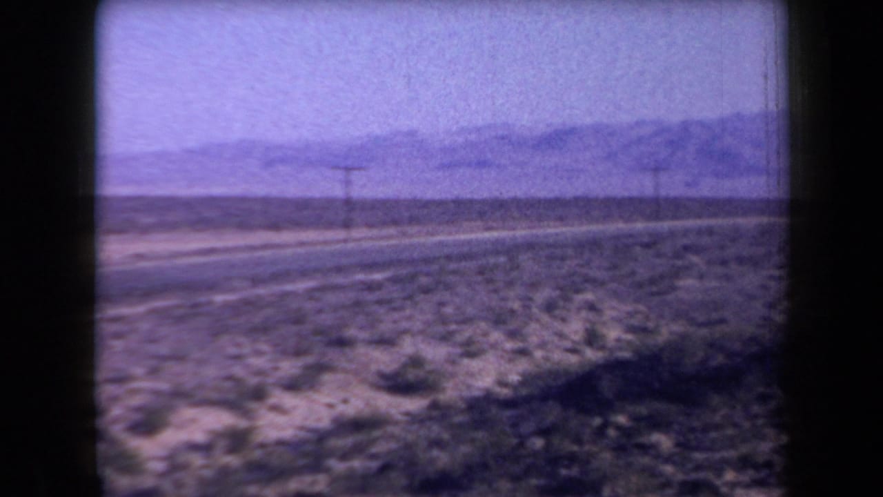 Open desert roadside with utility pole and mountains beyond.