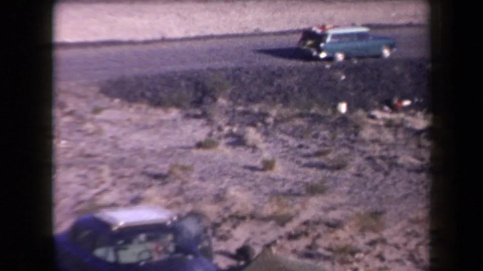 1958 Arizona roadside view with a turquoise station wagon in the distance and a dark blue sedan entering the lower foreground.
