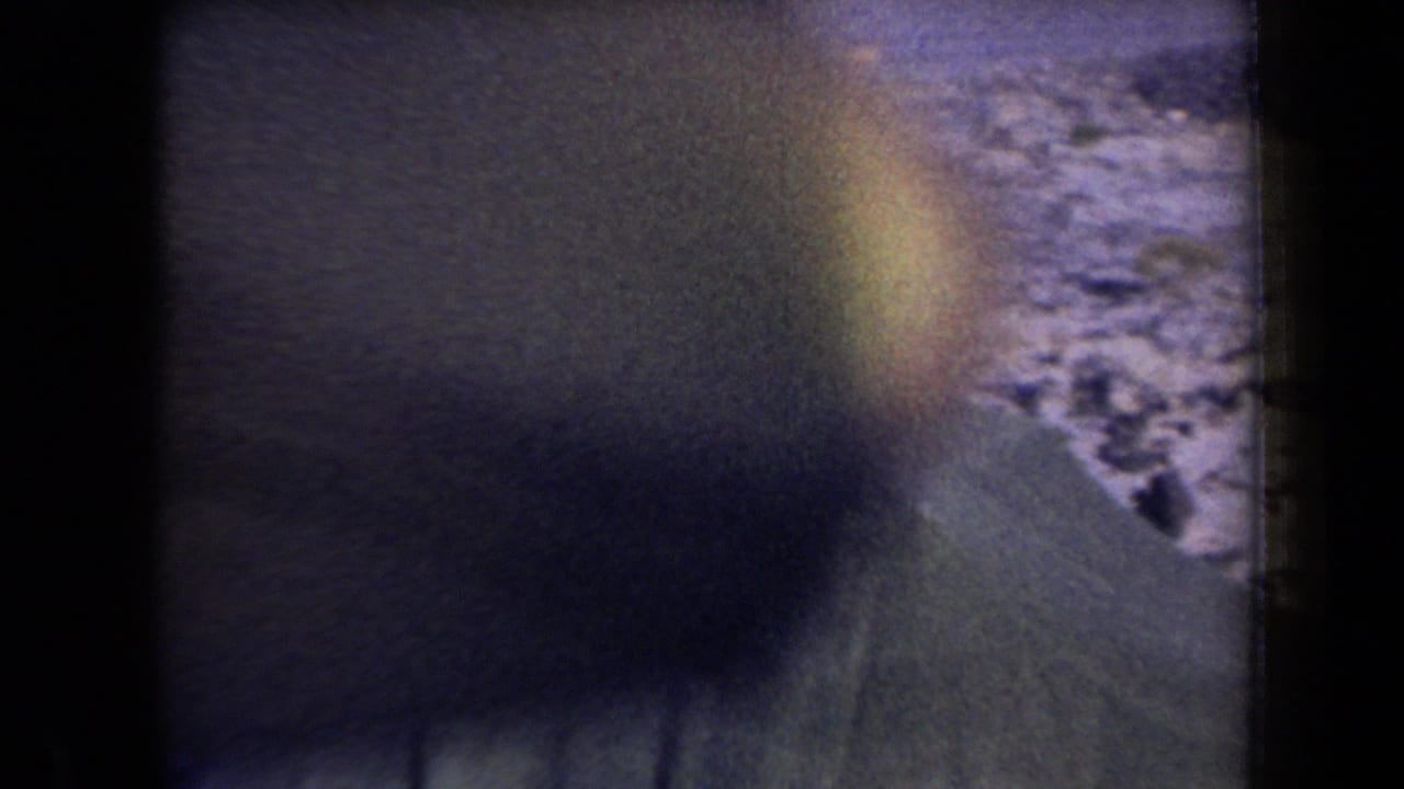 Blurred flashlight-lit view of a person near rough ground at night.