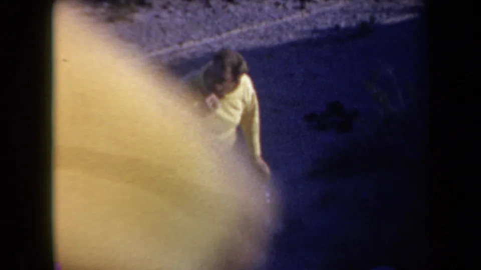 Overhead 8mm view of the man in a yellow shirt at the Arizona campsite, partly washed by flashlight glare while brushing his teeth.
