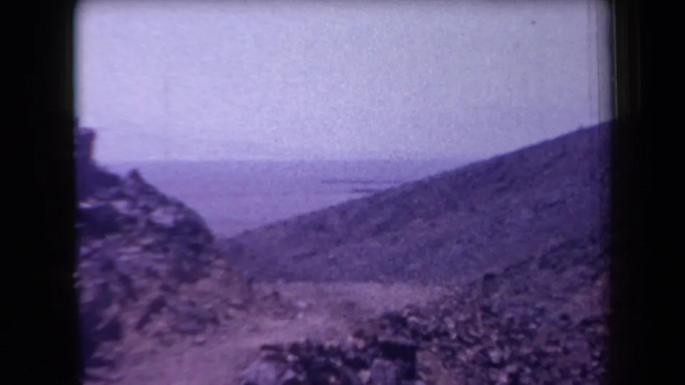 1958 Arizona home-movie view of loose rocks, sloping barren terrain, and a distant hazy horizon.