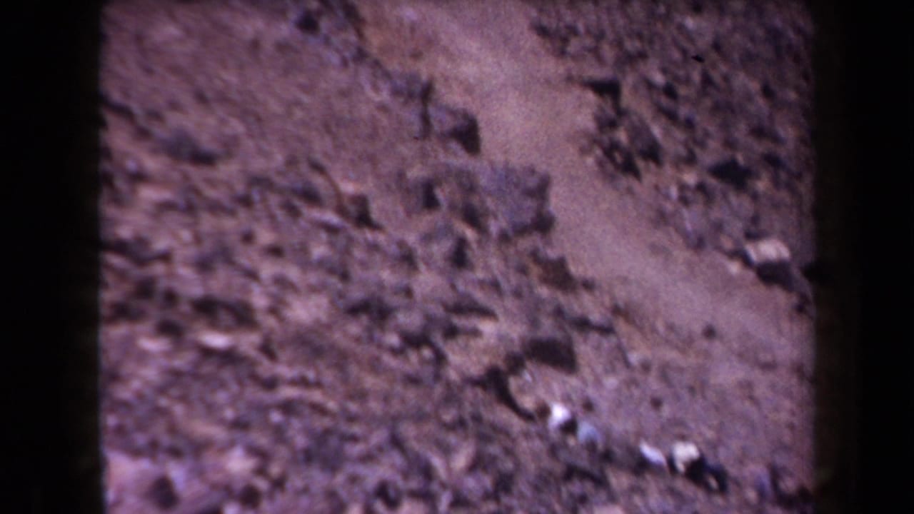 Rocky Arizona slope with scattered stones and scrub appears in soft, color-shifted 1958 8mm footage.