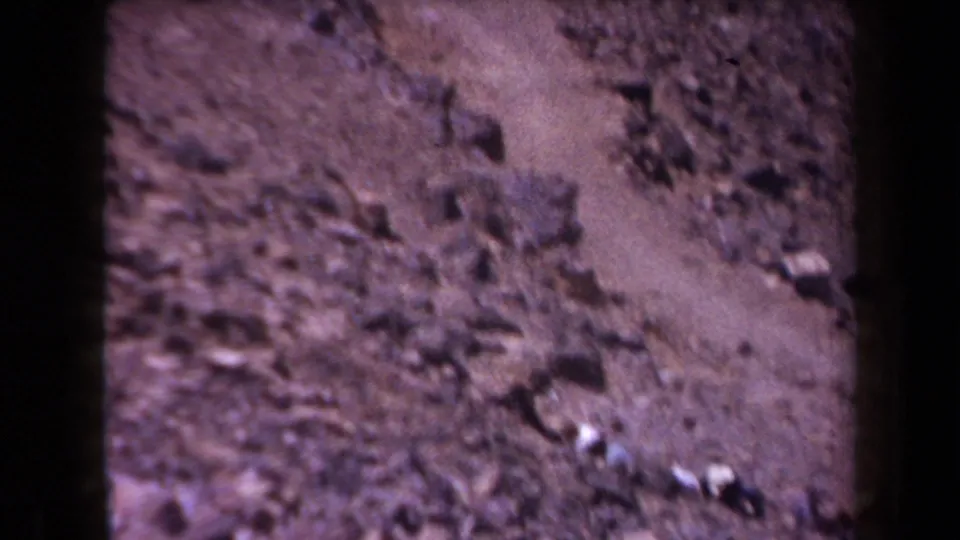 Rocky Arizona slope with scattered stones and scrub appears in soft, color-shifted 1958 8mm footage.
