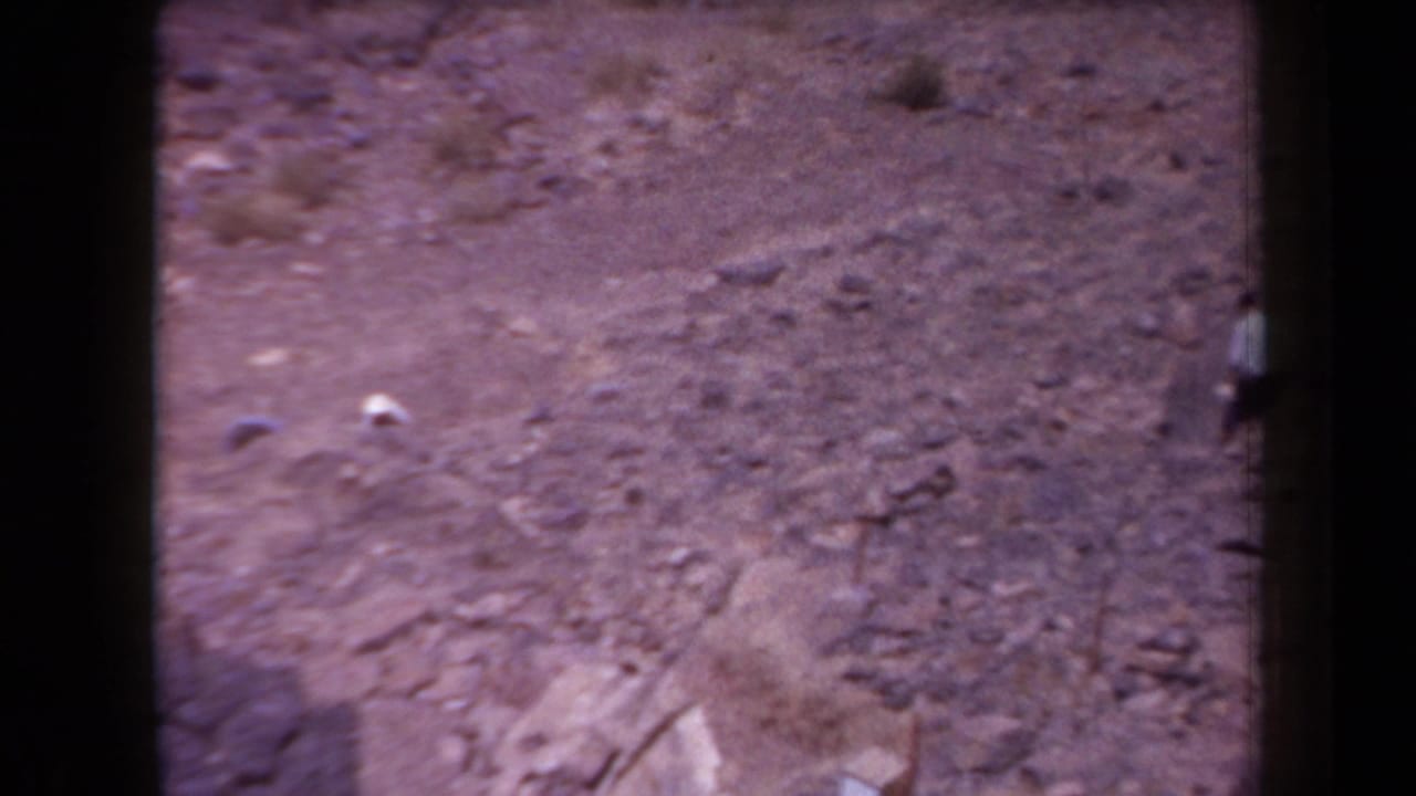1958 Arizona 8mm frame showing rocky desert terrain from an elevated viewpoint, with soft focus and dark film-edge borders.