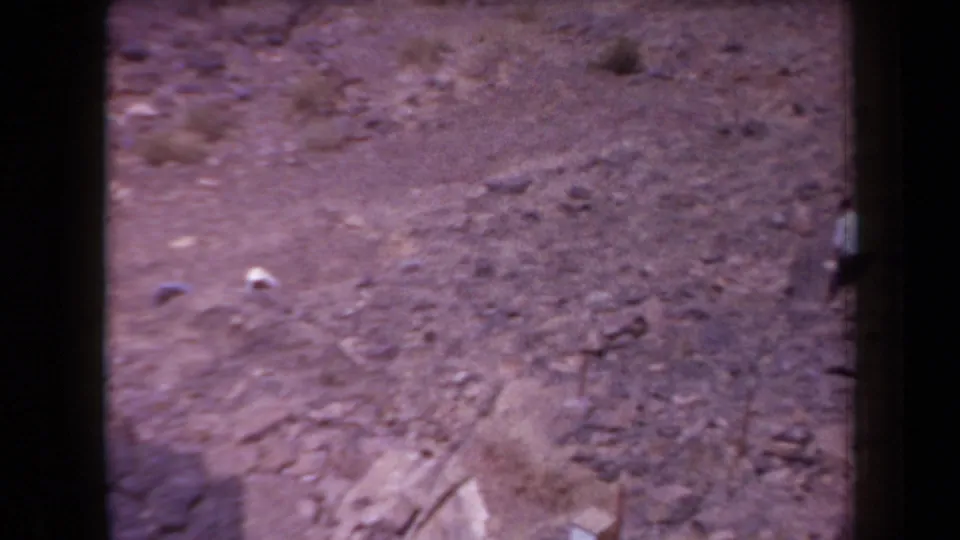 1958 Arizona 8mm frame showing rocky desert terrain from an elevated viewpoint, with soft focus and dark film-edge borders.
