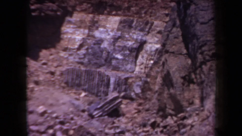 Close view of layered desert rock formations in Arizona, with rough ground and 8mm grain visible in the frame.