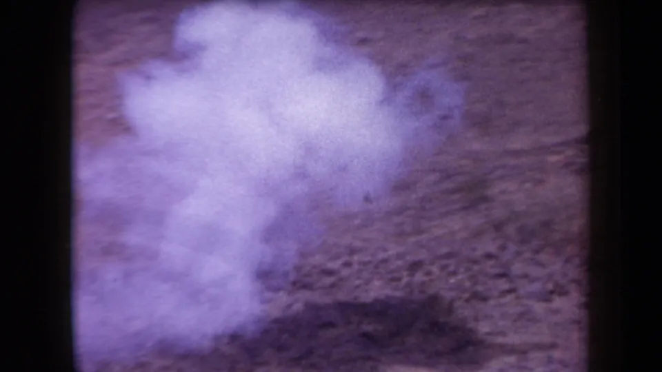 Hazy 1958 Arizona 8mm frame showing rocky desert ground with strong purple color fading and no clearly visible people.