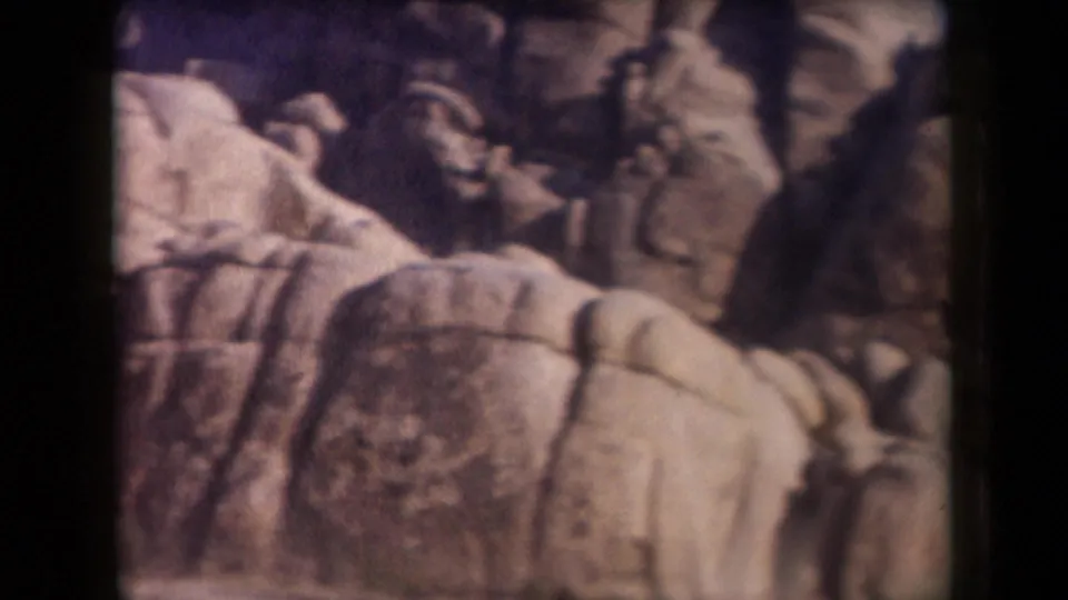 1958 Arizona 8mm frame with clustered rounded boulders, shadowed rock faces, warm color shift, and soft home-movie focus.
