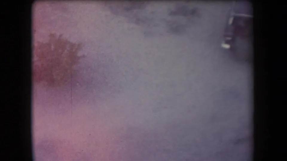 Faded 1958 Arizona 8mm frame with reddish brush, dusty road, and a car partly visible at the far right edge.