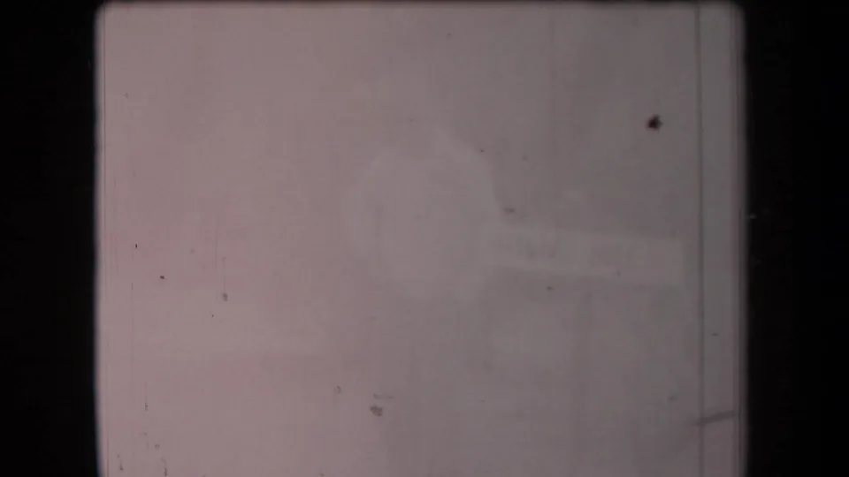 Degraded 8mm frame from the Arizona clip showing a soft outline of a tall adult near a low, sign-like form.