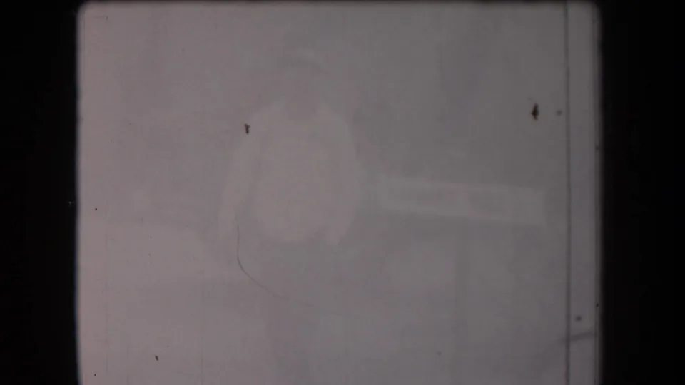 Final 1958 Arizona 8mm frame with a washed-out adult figure near an unreadable informational sign-like shape.