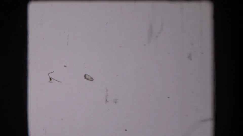 Pale, overexposed 8mm frame from the Arizona home movie, with dust and scratches obscuring any distinct scene detail.