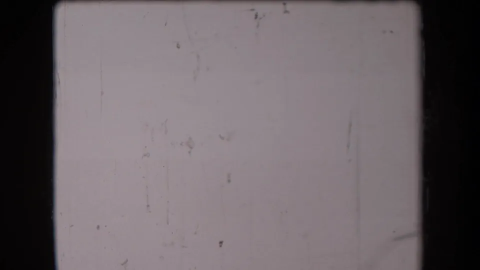Gray, faded 8mm frame from the 1958 Arizona footage, showing scratches and surface wear with the subject largely obscured.