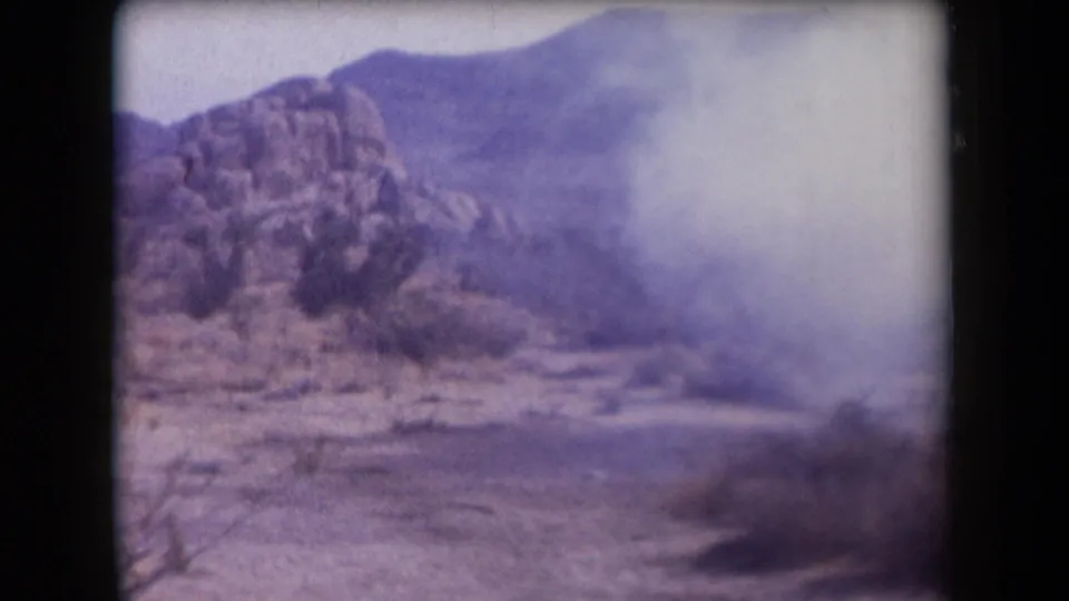 1958 Arizona 8mm frame with a pale plume drifting across the right side of a desert mountain view.