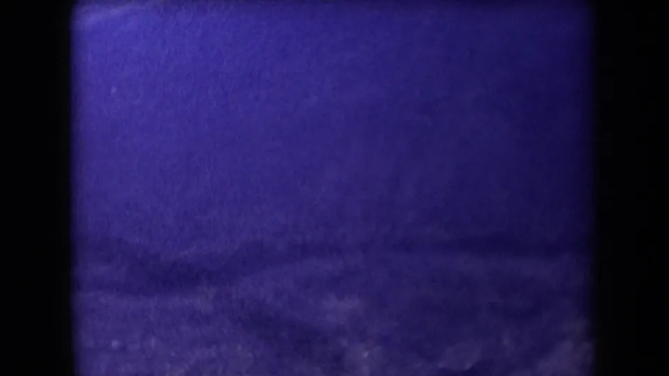 Purple-shifted 8mm frame of an Arizona hillside or valley area with dark film borders and low visible detail.