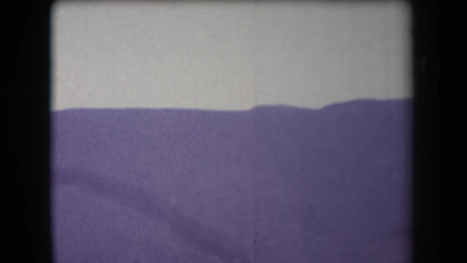 1958 Arizona home-movie frame showing a distant ridgeline under pale sky with strong grain and faded color.