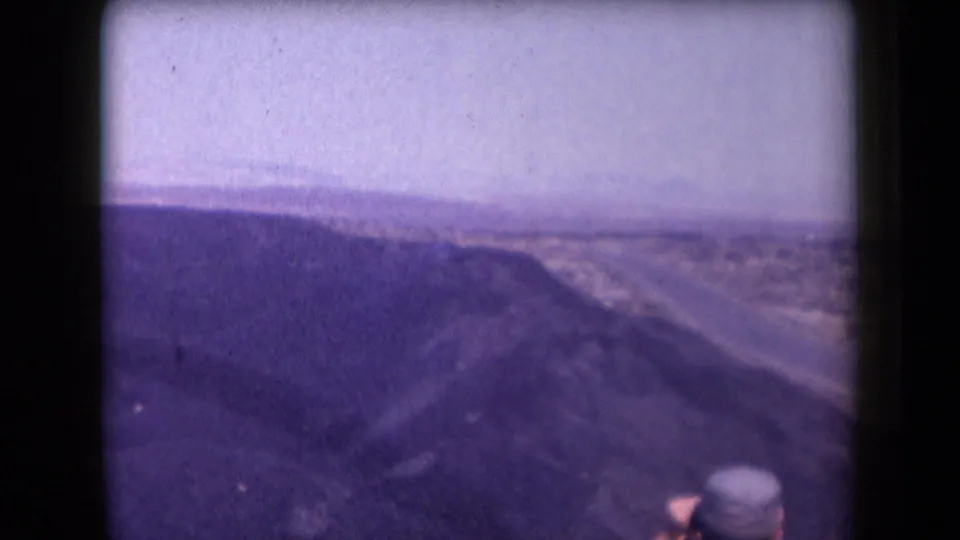 1958 Arizona frame of a broad canyon view and desert road, with a partially visible person in a hat at the lower edge.