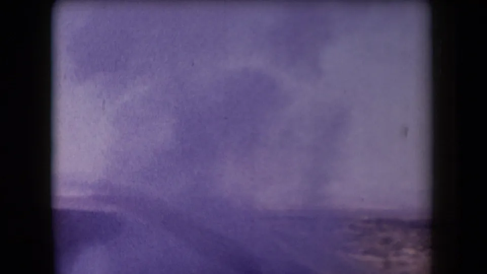 1958 Arizona 8mm frame showing a broad smoke plume spreading above a desert horizon after an apparent explosion.