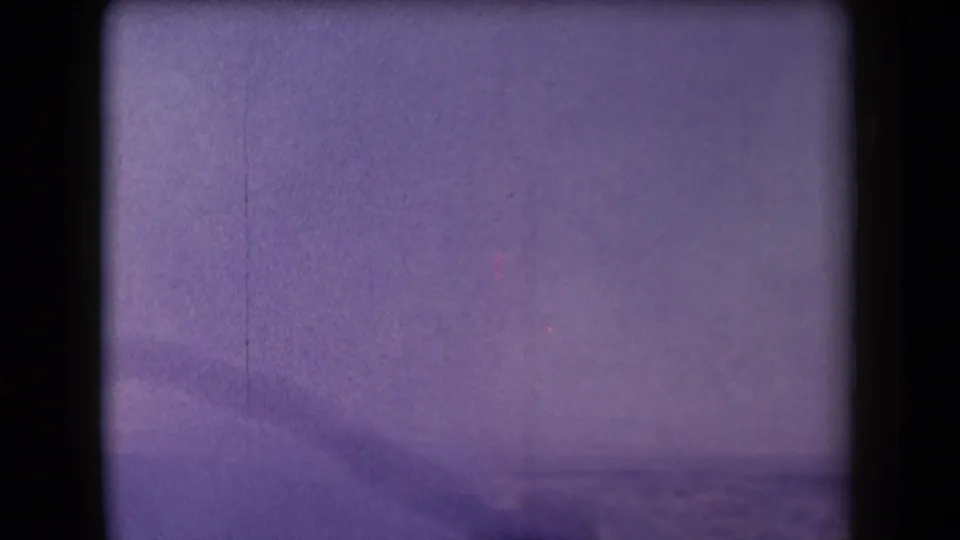 1958 Arizona 8mm frame with a purple cast, soft sky or steam, distant landscape, and dark gate-edge shadows.