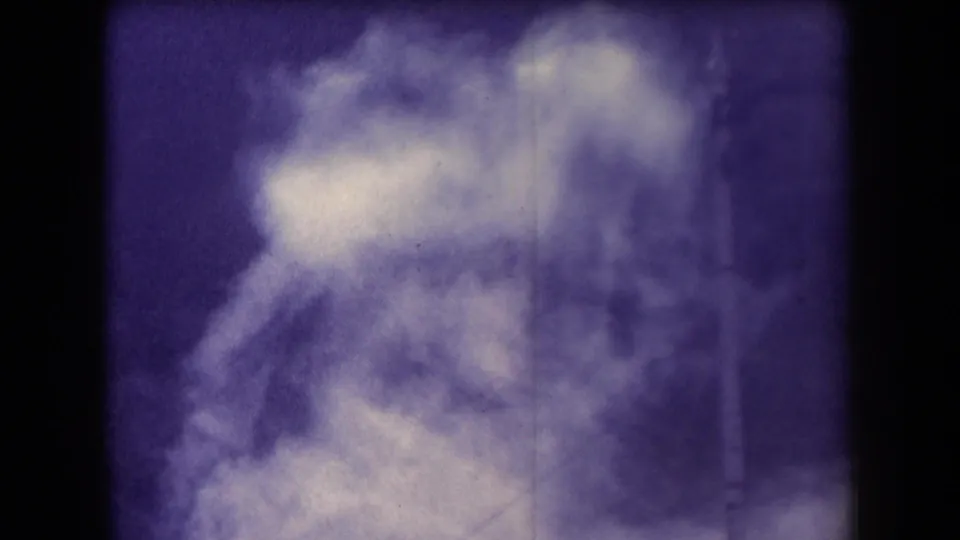 Purple-cast 1958 Arizona 8mm frame showing dense pale steam or spray against a soft outdoor background.