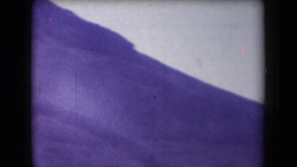 1958 Arizona 8mm frame showing a hazy, purple-cast mountain slope with heavy gate edges and soft exposure.