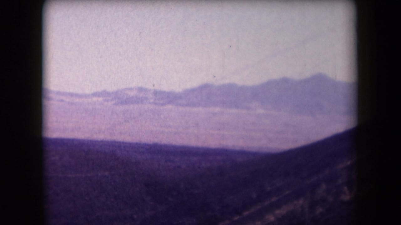 Distant mountains beyond a dark desert foreground under a pale sky.