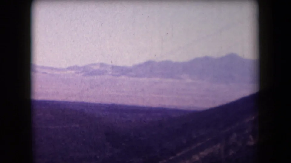 1958 Arizona desert landscape with low mountains in the distance and dark scrubland in the foreground.
