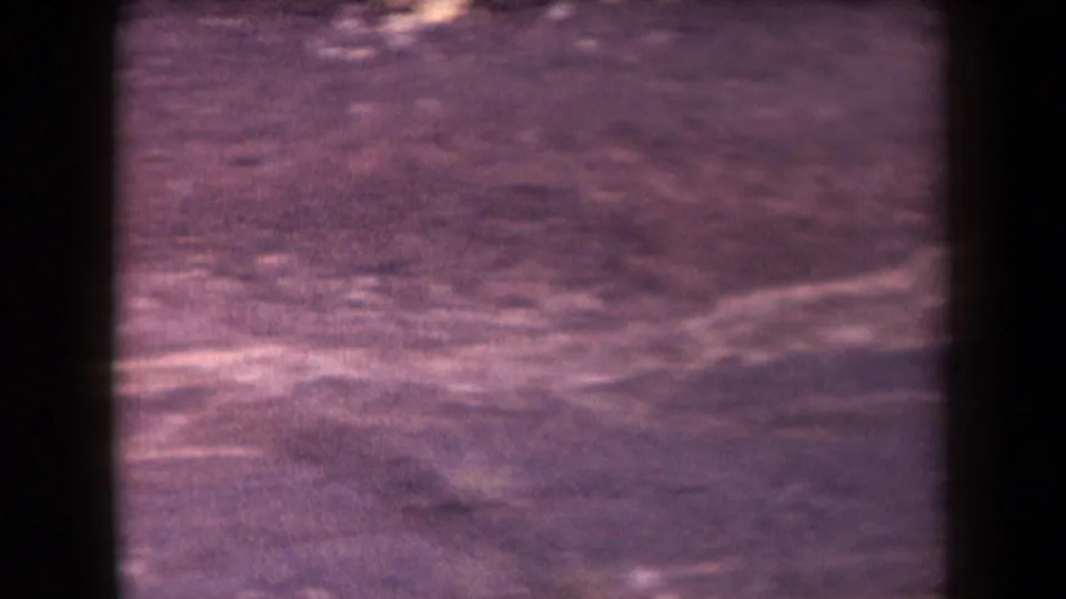 1958 Arizona home-movie frame showing a soft, purple-tinted high-angle view across barren desert terrain.