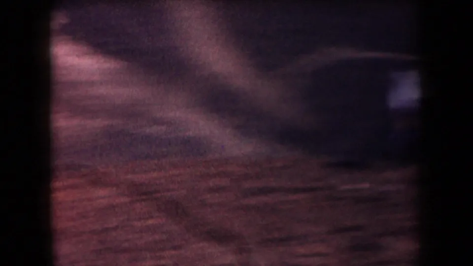Soft, motion-blurred 8mm frame with reddish desert ground and indistinct road texture, likely during camera movement.
