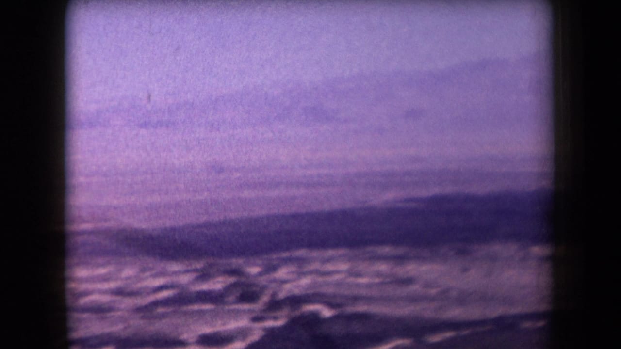 Wide desert flats and distant hills seen through a purple-tinted film frame.