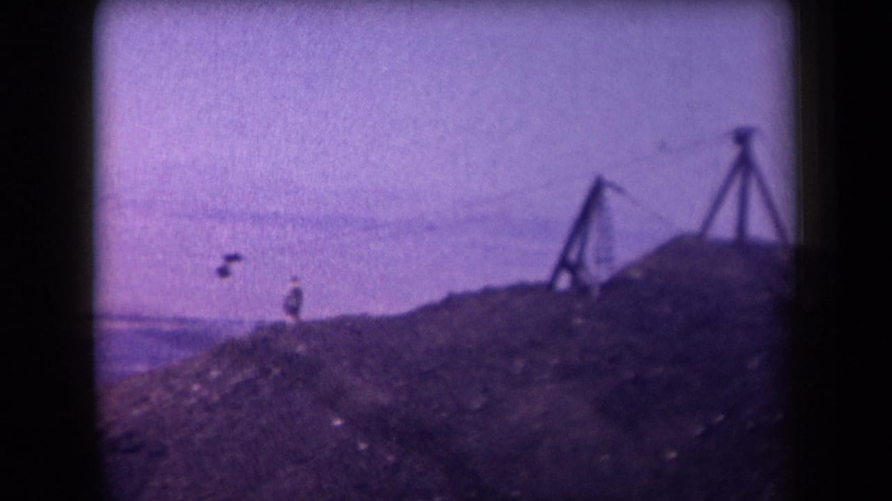 A figure appears suspended on a zipline above a desert slope with wooden supports nearby.