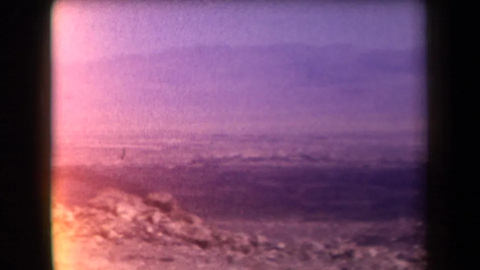1958 Arizona 8mm still showing dry ground, a distant mountain ridge, and heavy purple fading through a dark window frame.