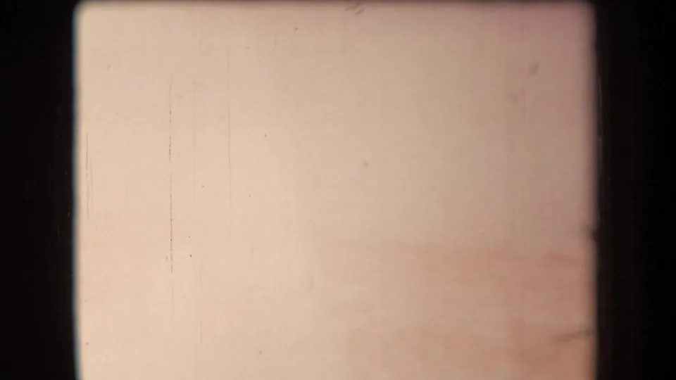 Mostly blank, overexposed 8mm frame with pale color, small surface marks, and visible film gate borders.