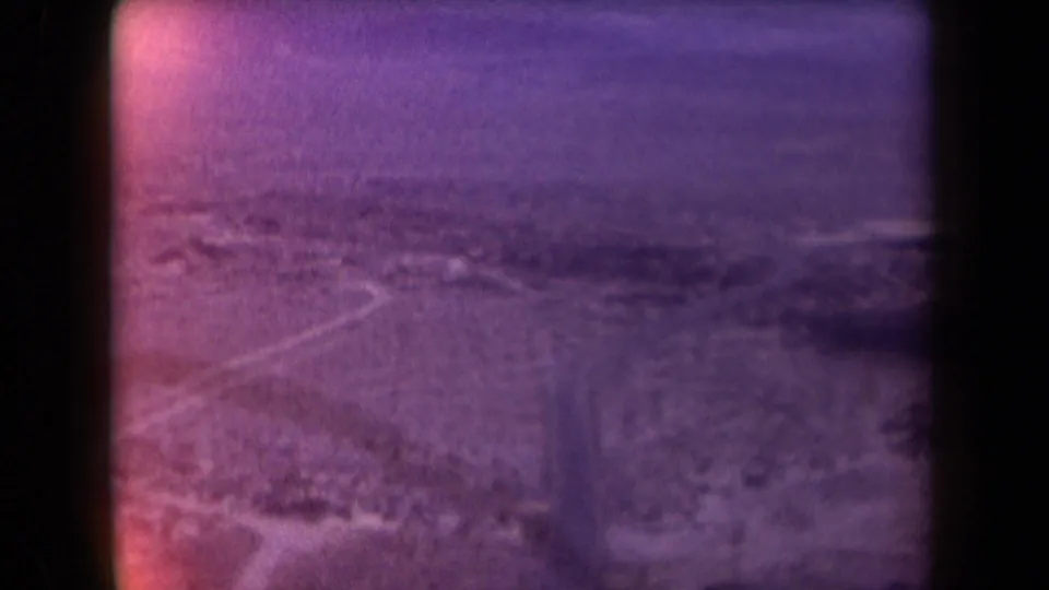 Aerial 1958 Arizona view of a pale road running through desert hills and distant mountain forms.