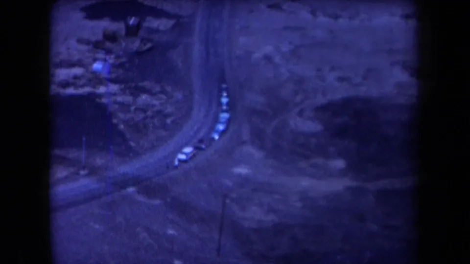 1958 Arizona aerial frame showing a winding road curve with several small cars visible in rugged desert terrain.