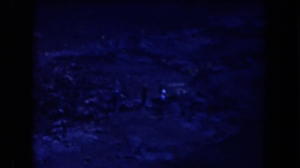 A distant man is faintly visible near brush and rocks in blue-tinted 1958 Arizona desert footage.