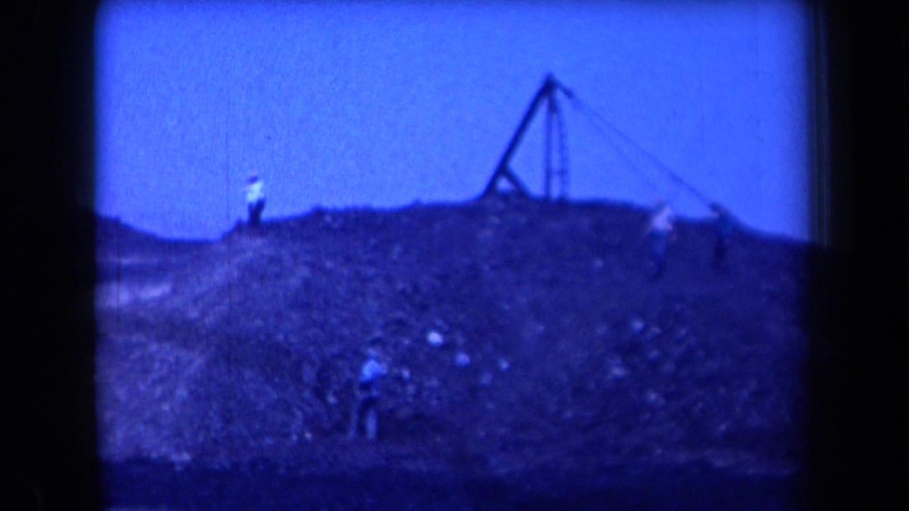 A wide 1958 Arizona view shows small figures on a coal mound near a derrick-like structure under a blue-tinted sky.