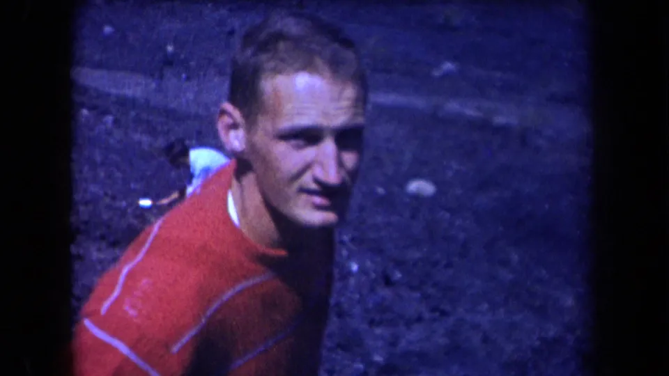 A man in a red striped shirt looks toward the camera while standing or crouching on a coal slope in 1958 Arizona footage.