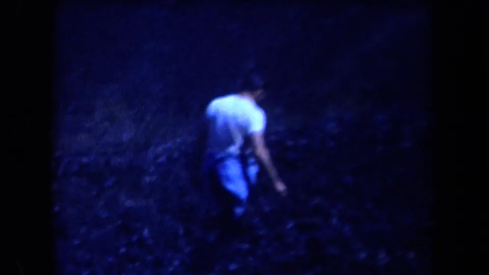 A man in a light short-sleeved shirt walks away through rough brush on a blue-tinted Arizona mountain slope.