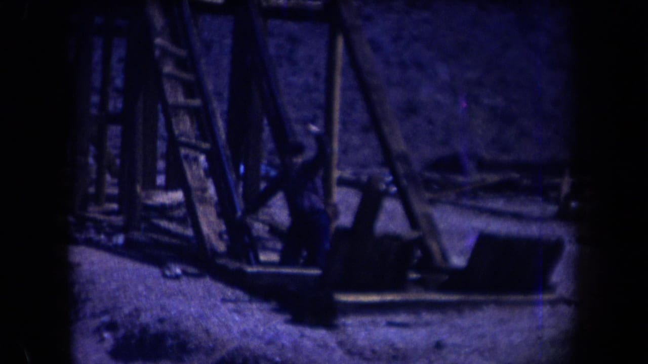 1958 Arizona 8mm frame showing weathered timber mine supports and equipment in a rocky desert setting.