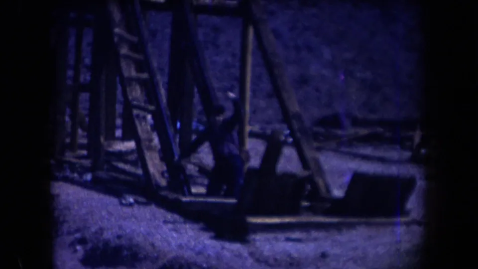 1958 Arizona 8mm frame showing weathered timber mine supports and equipment in a rocky desert setting.