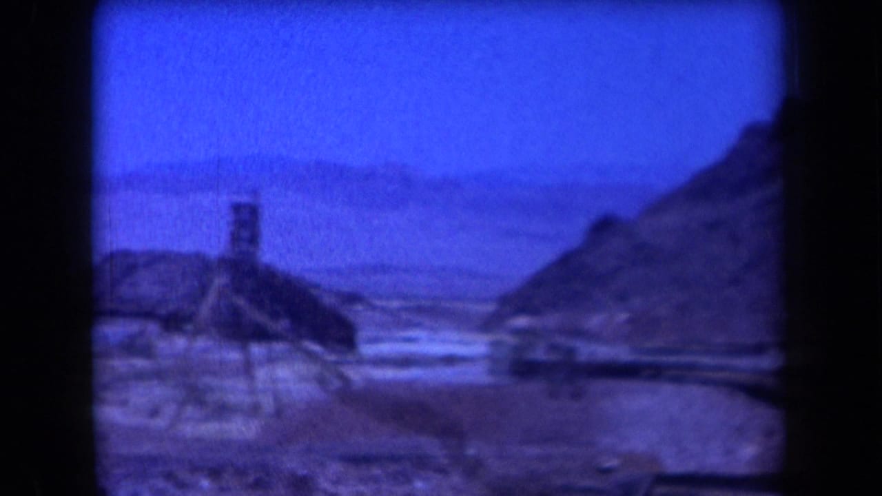 1958 Arizona desert view with a small tower-like mining structure among rocky hills beneath a blue sky.