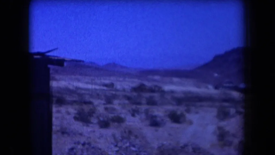 1958 Arizona home-movie frame with open desert, distant hills, scrub, and a dark vertical edge from the film scan.