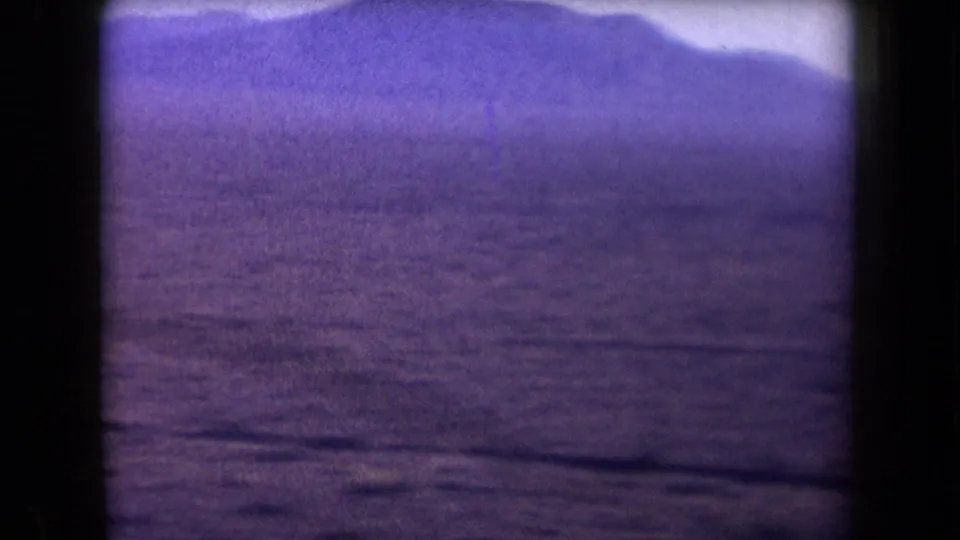1958 Arizona 8mm frame of an expansive desert plain with a distant mountain ridge and no clearly visible people in this frame.